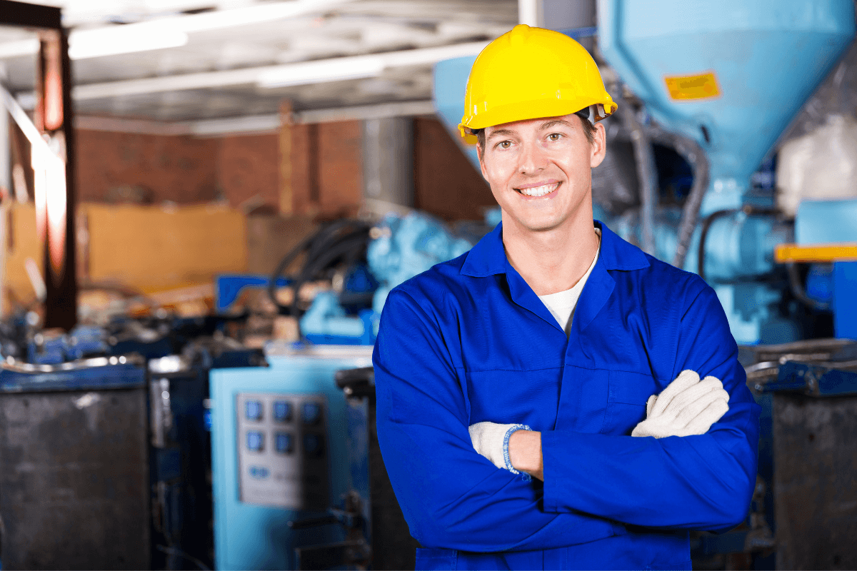 young male worker in yellow hard hat and blue coveralls