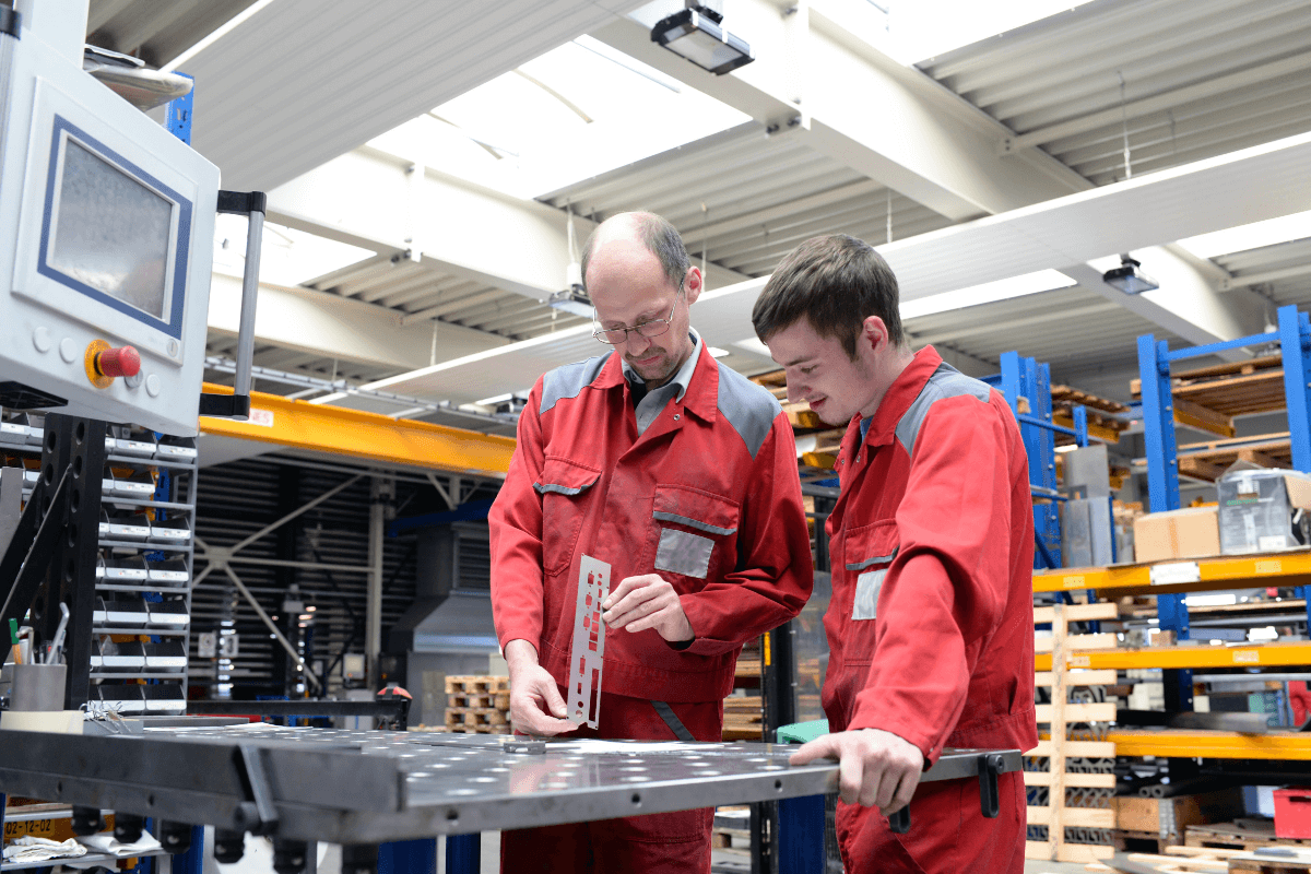 two male workers in red coveralls standing at a table