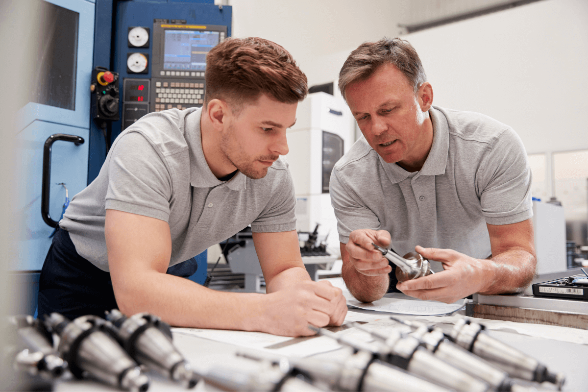 two men in a manufacturing facility looking at parts