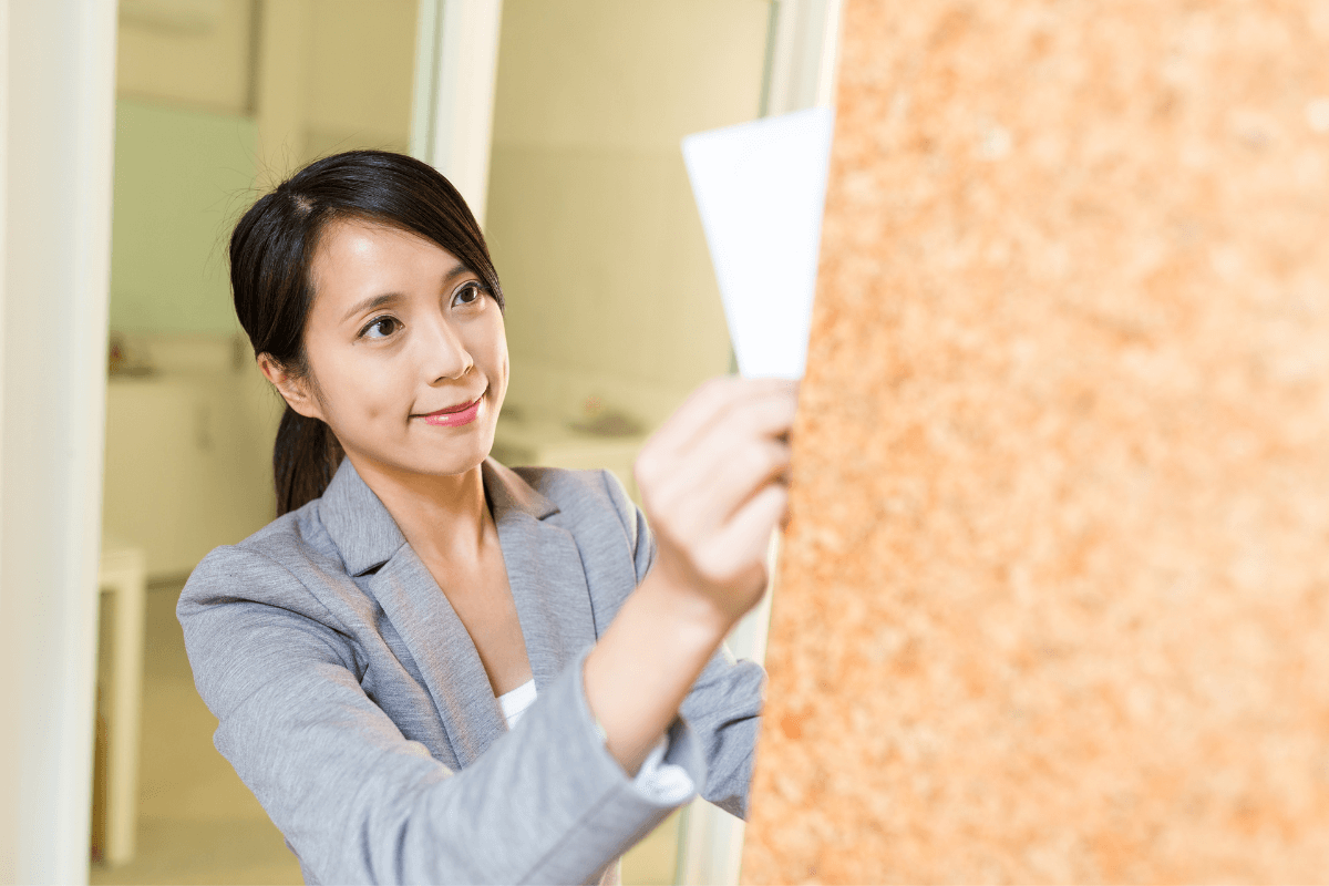 young Asian woman posting a piece of paper on the wall