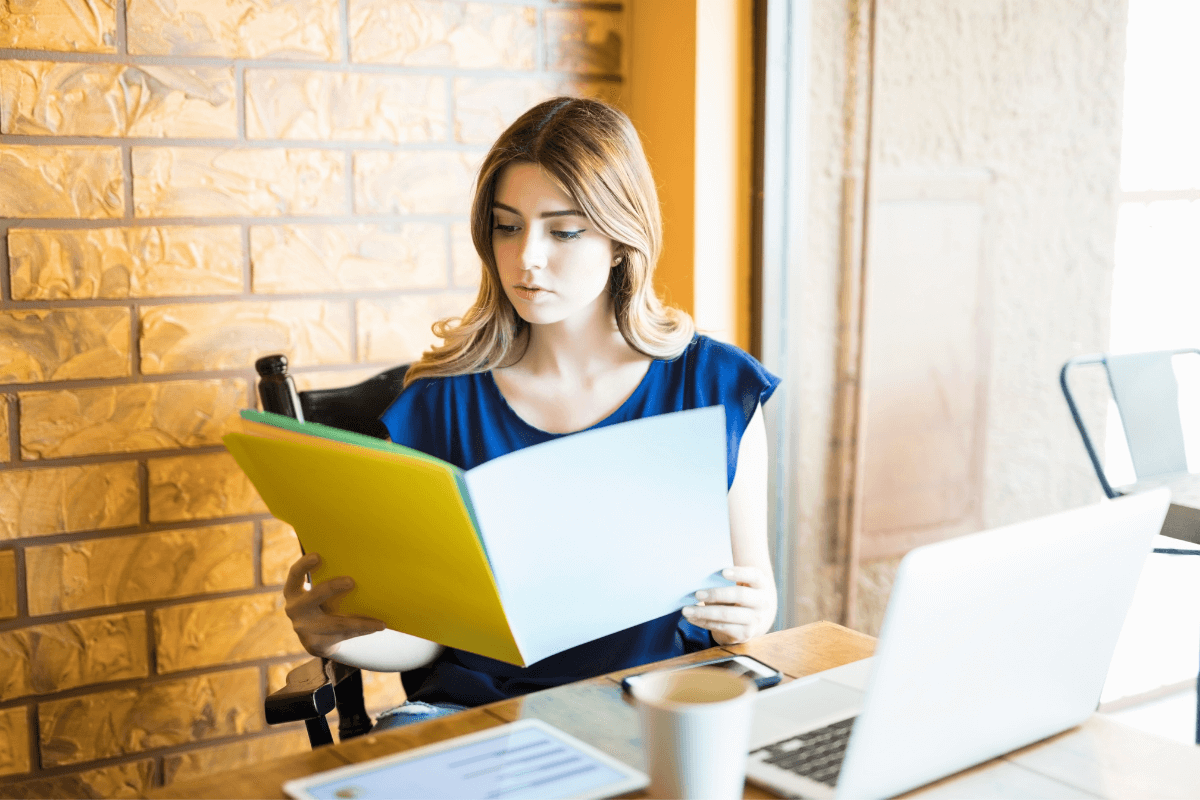 young woman looking at a file folder while sitting at a desk